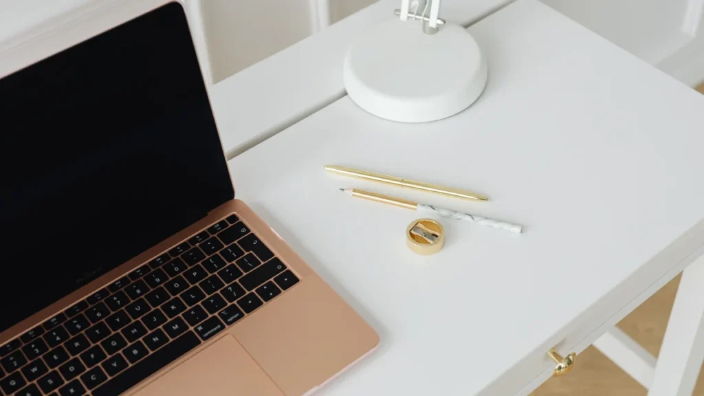 Escritorio blanco minimalista con un laptop y luz natural suave evocando orden y claridad