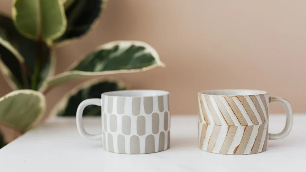 Dos tazas de café minimalistas sobre una mesa iluminada por el sol natural