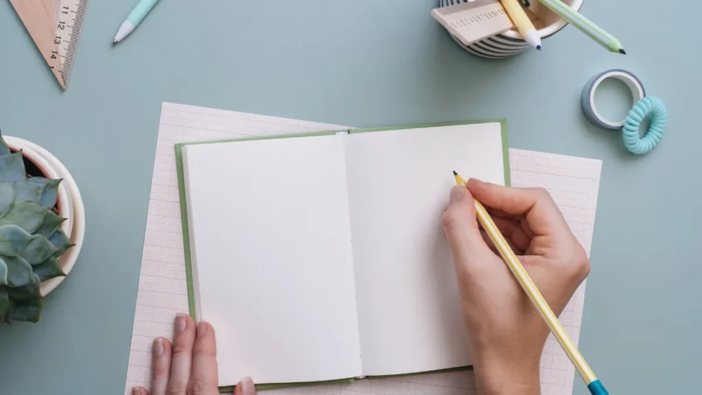 Manos de una mujer escribiendo reflexiones en un cuaderno minimalista