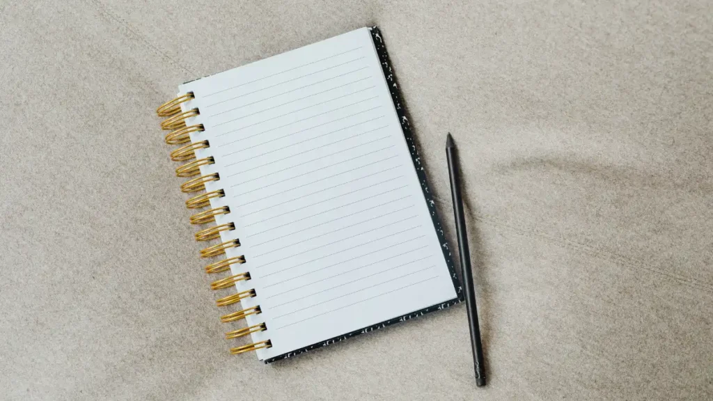 Un cuaderno de notas abierto con páginas limpias y una pluma fina sobre un fondo neutro