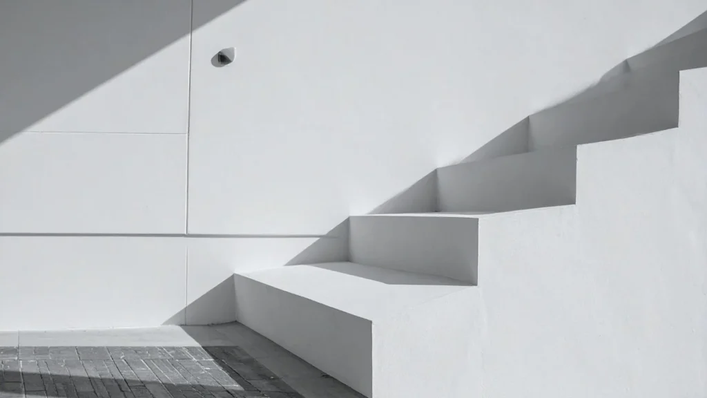 Una escalera arquitectónica minimalista de cemento blanco con líneas de sombra limpia bajo la luz del sol