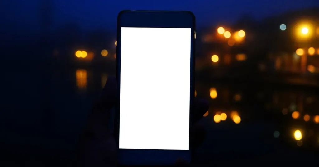 Pantalla de teléfono iluminada en la oscuridad, representando un estímulo digital que atrae la atención