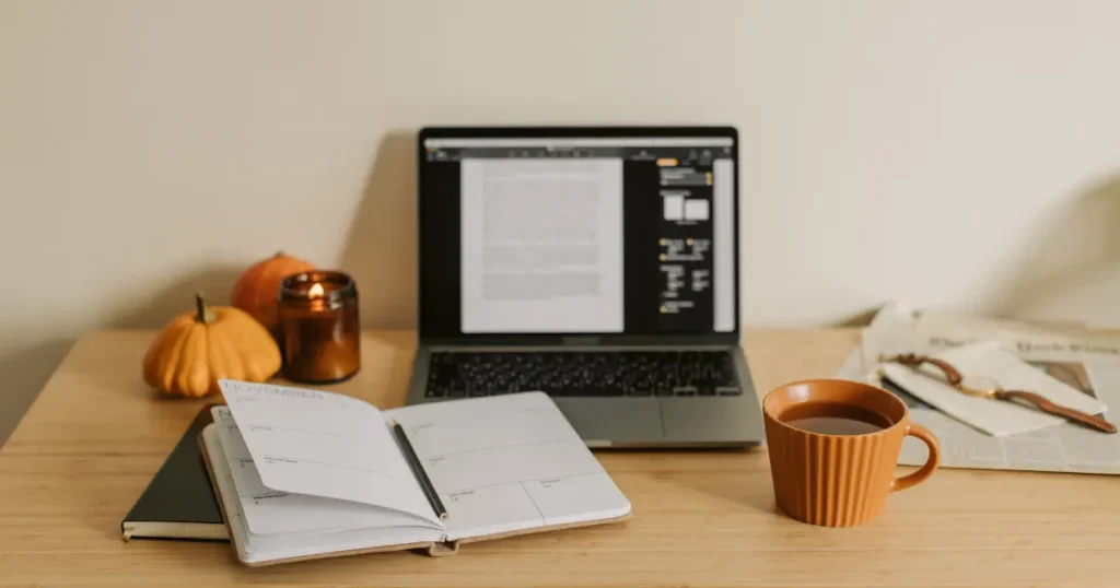 Portátil y cuaderno abiertos sobre una mesa, representando una tarea interrumpida que necesita ser retomada