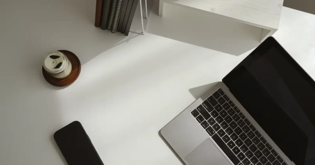 Espacio de trabajo con portátil y varios elementos alrededor, representando atención fragmentada y cambio entre tareas