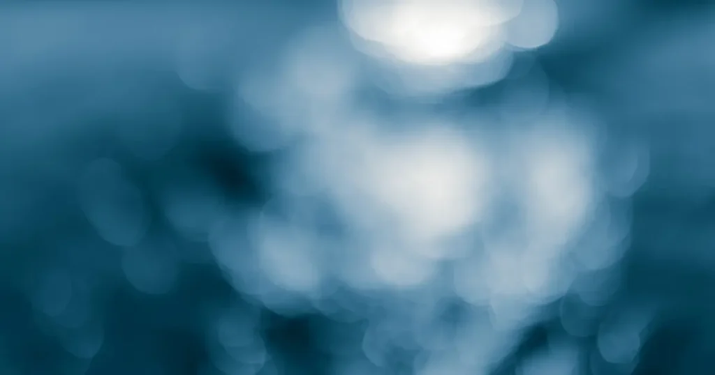 Reflejos azules desenfocados sobre el agua, representando una percepción saturada por múltiples estímulos