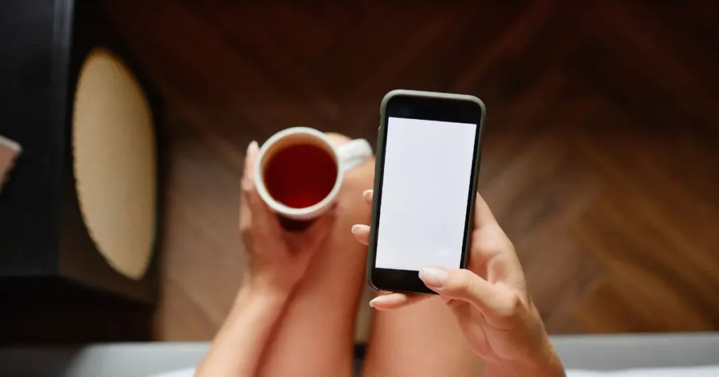 Persona usando el teléfono móvil en la cama durante la rutina de la mañana